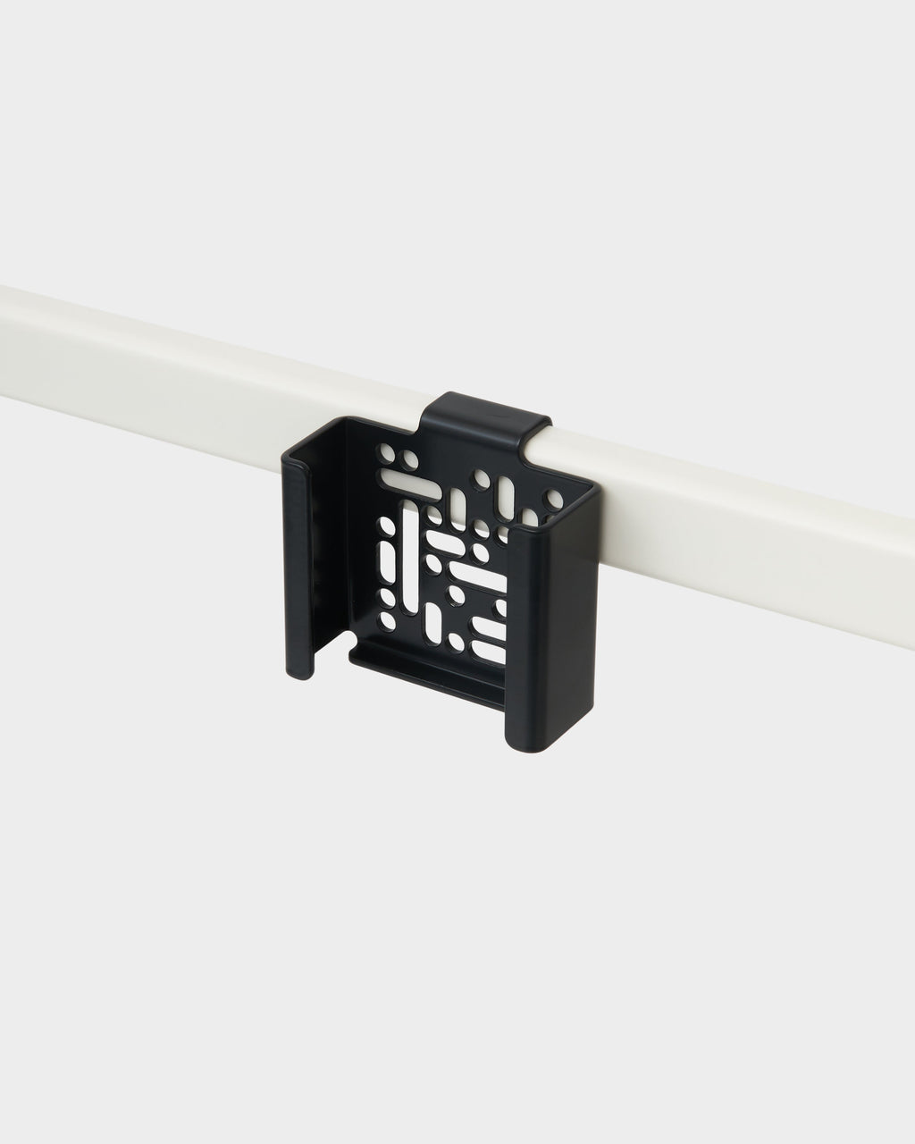 Charcoal Apple TV 4K Mount clipped onto a white desk frame bar, angled studio packshot showing vented bracket