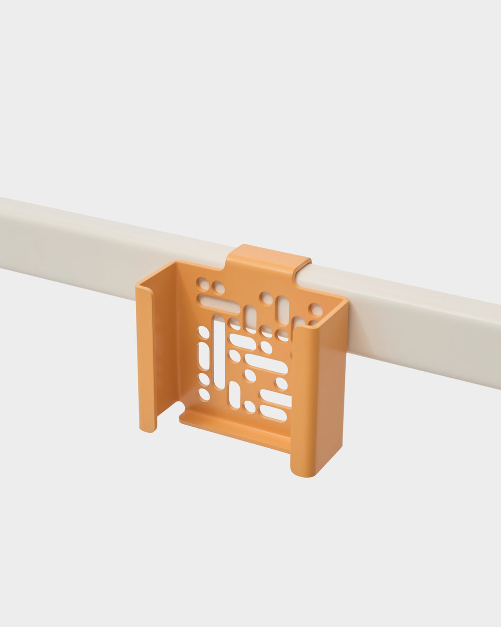 Apricot Apple TV 4K Mount hooked over a pale railing in a studio packshot, angled to show its perforated cradle