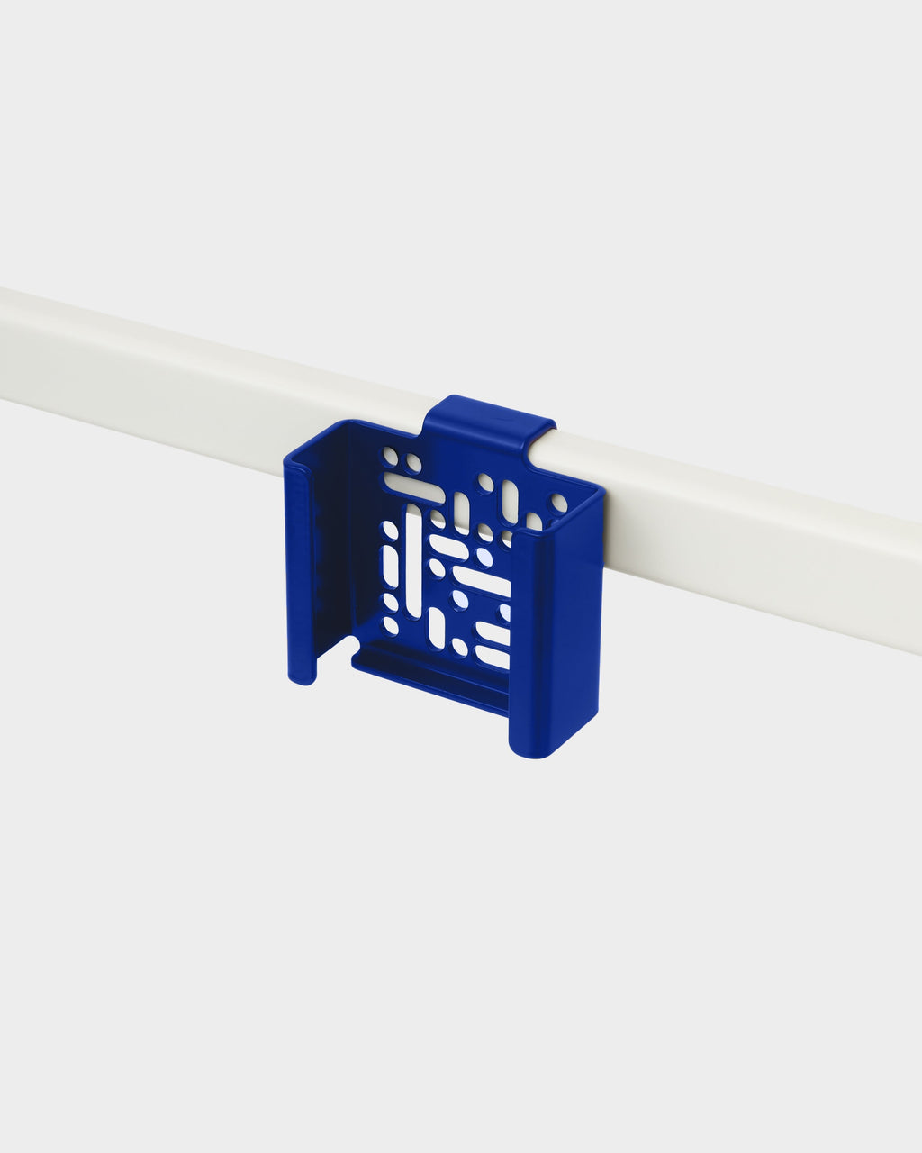 Ultra Marine Apple TV Mount clipped onto a white desk rail in a studio packshot, angled to show perforated cradle