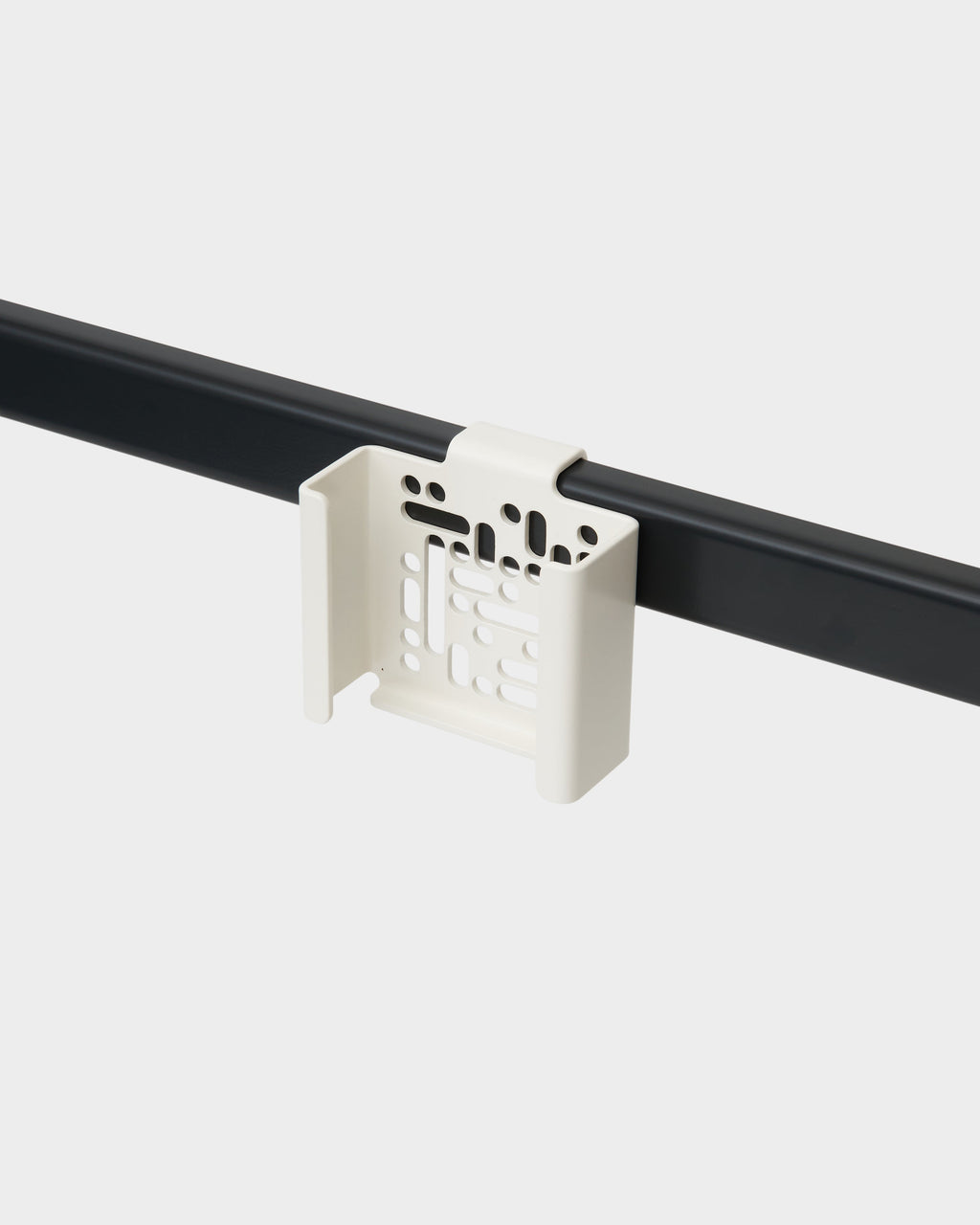 Pearl Apple TV Mount clipped onto a black rail, angled studio view showing its perforated cradle design