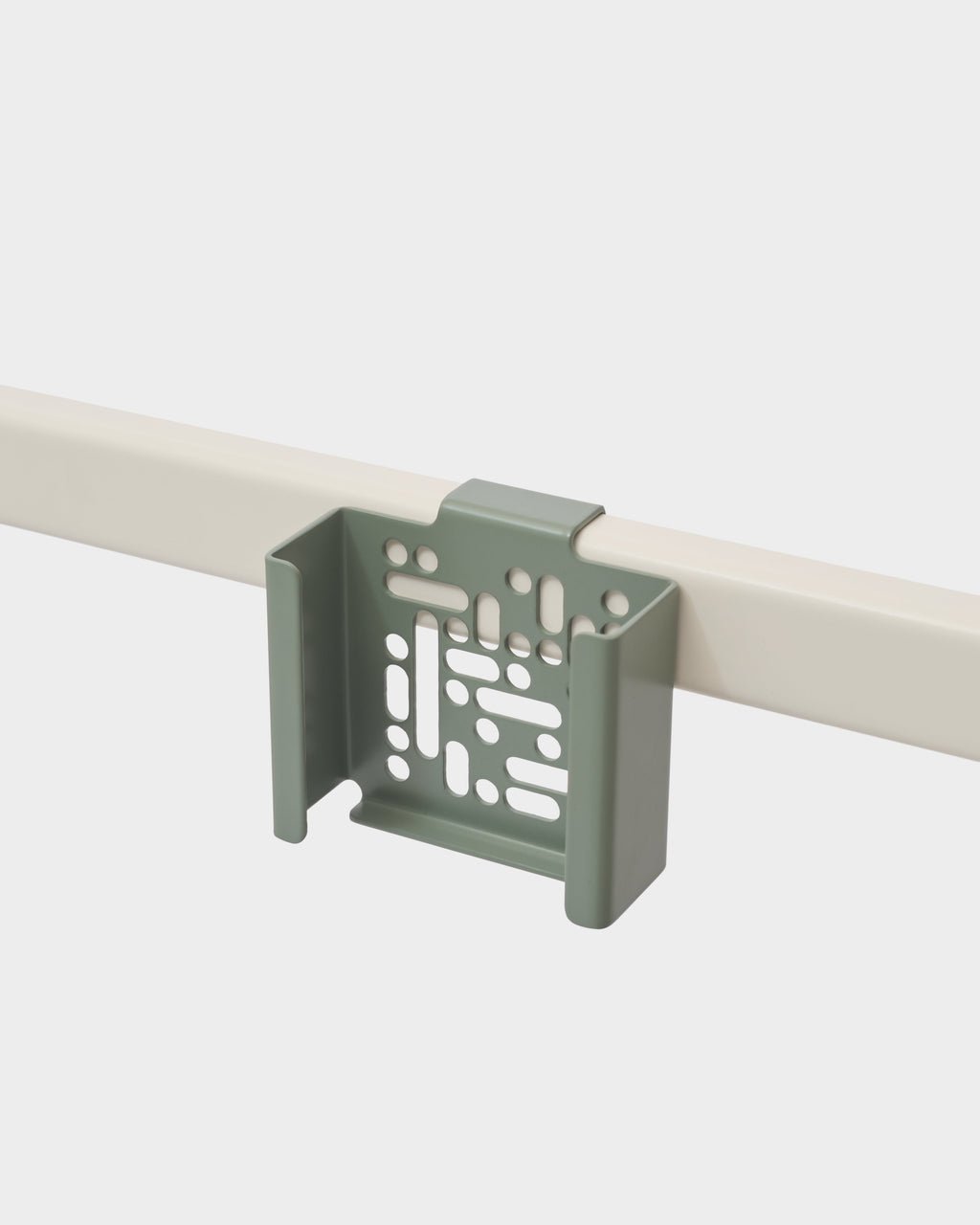 Mossy Green Apple TV Mount hooked over a slim wall rail in a studio shot, angled view showing perforated tray design