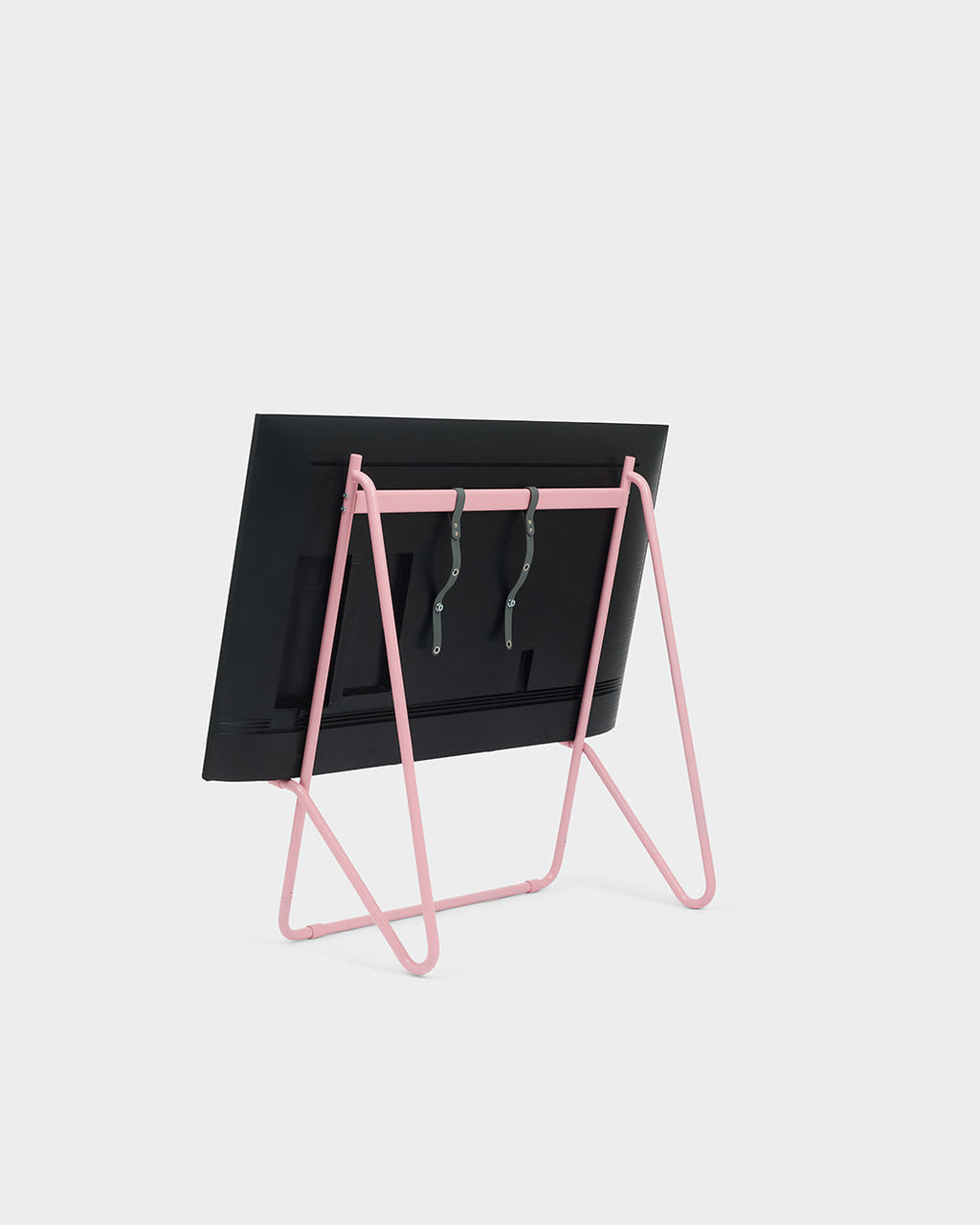 Rear view of Bloom in Bubble Gum low stand holding a mounted TV with grey straps, studio packshot on white