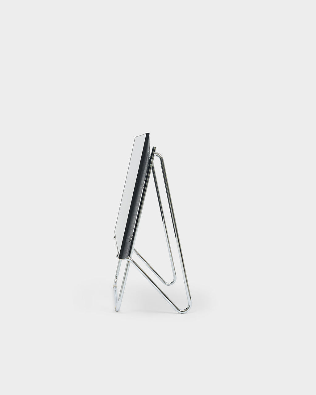 Side profile studio packshot of Bloom in Chrome low stand, showing its bent tubular frame supporting an angled panel