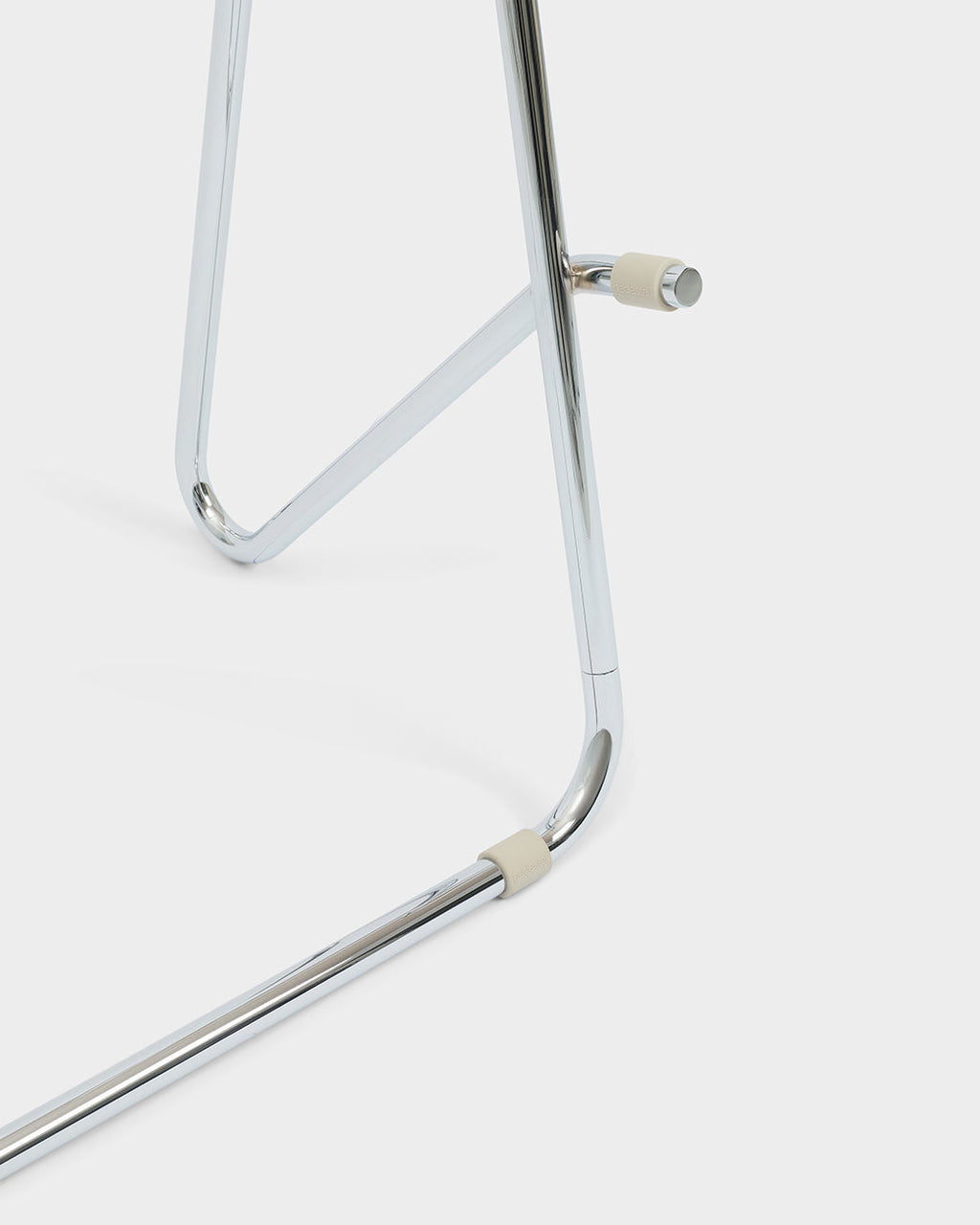 Close-up of Bloom Stands Low in Chrome, studio packshot detailing polished tubular legs with cream rubber caps
