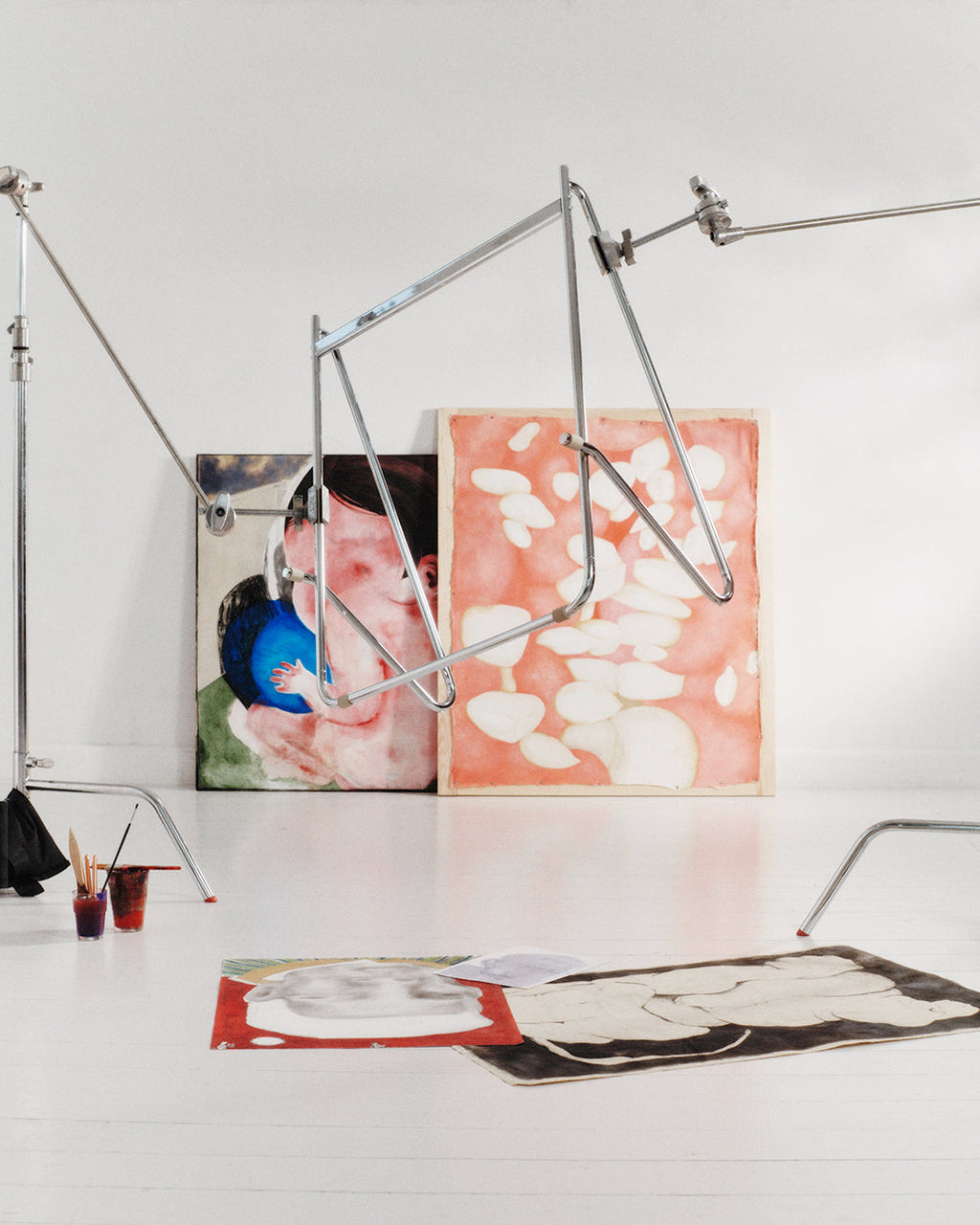 Bloom in Chrome (Stands Low) angled in a white artist studio among leaning paintings, floor artwork and paint jars