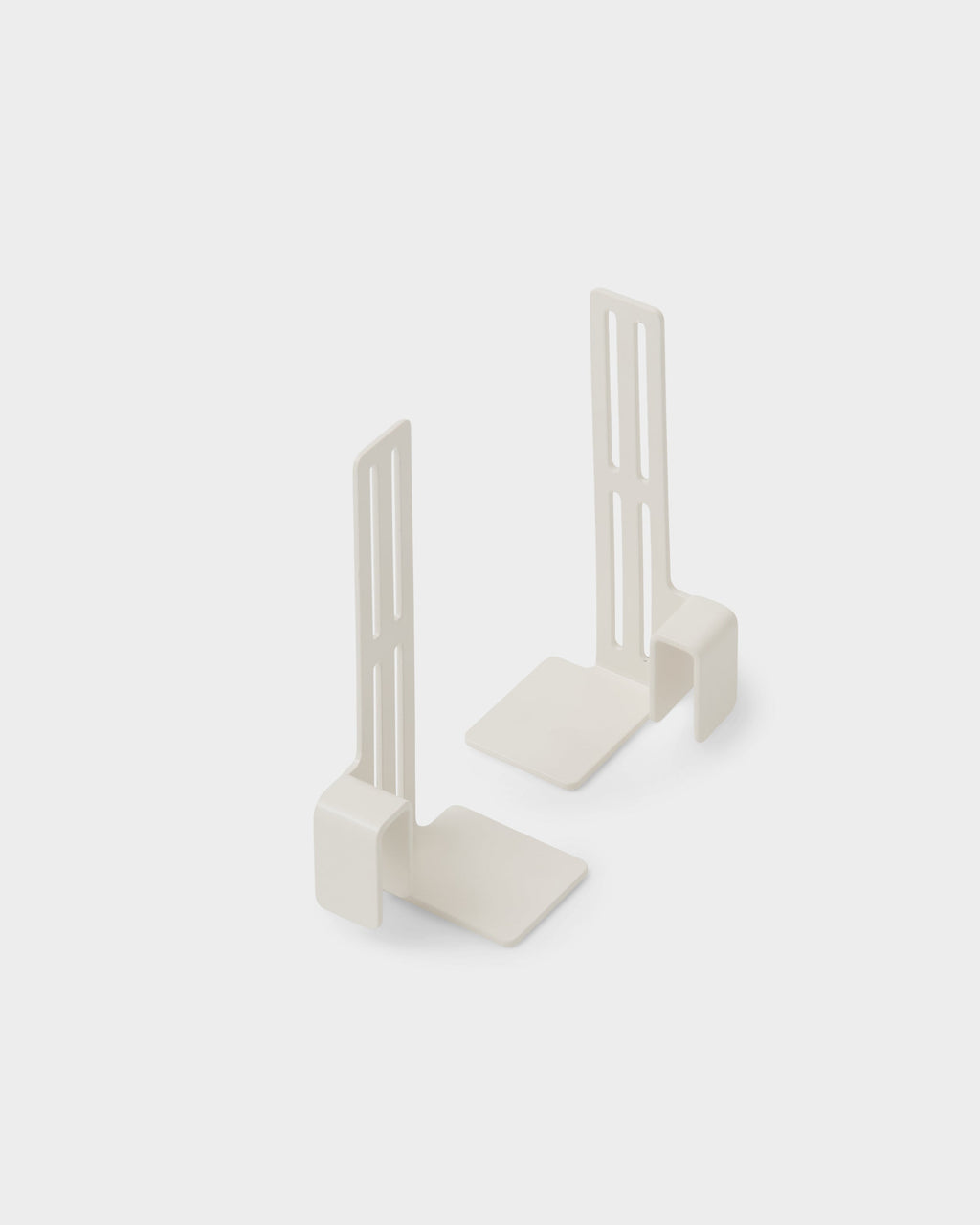 Pair of Box Mount brackets in Pearl standing upright on a light studio backdrop, angled view showing slotted arms and bases