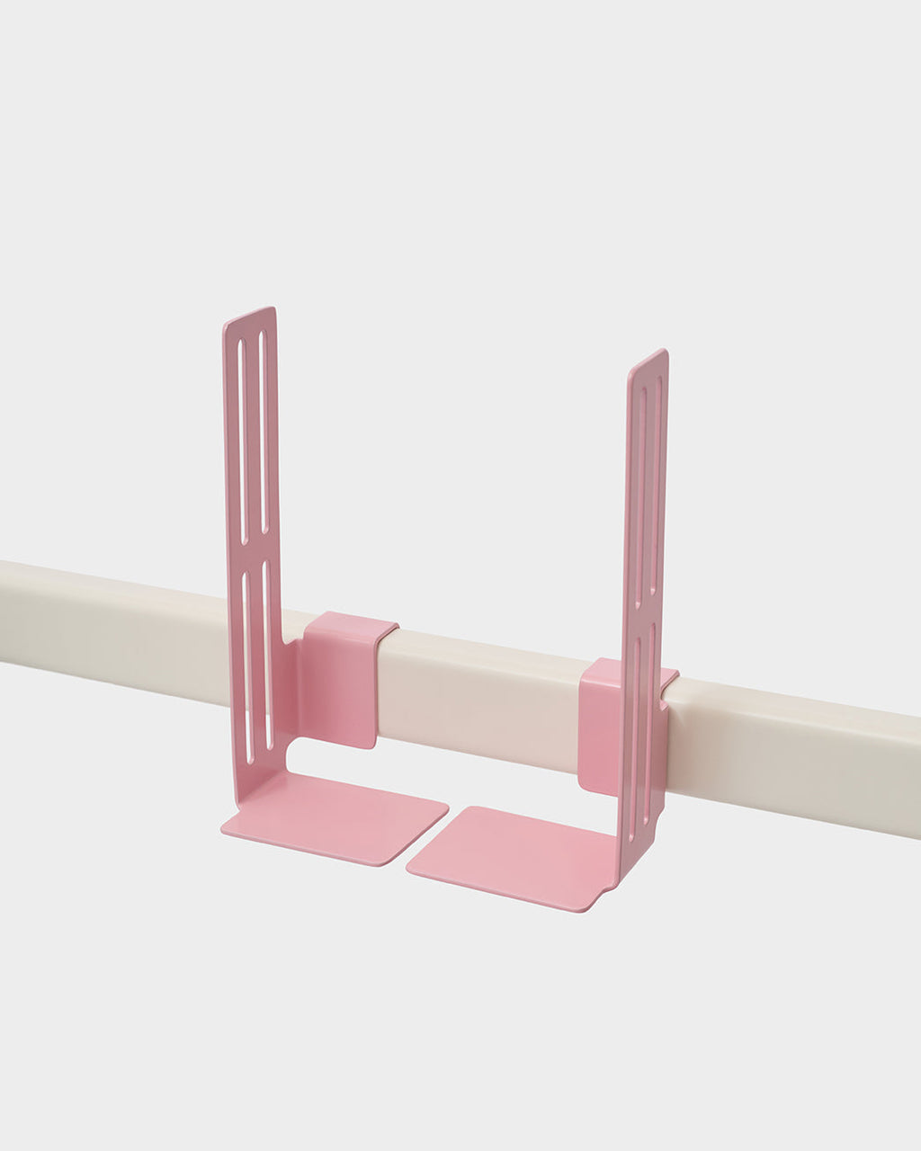 Pair of Bubble Gum pink Box Mount brackets clamped onto a cream rail in a studio packshot, angled side view