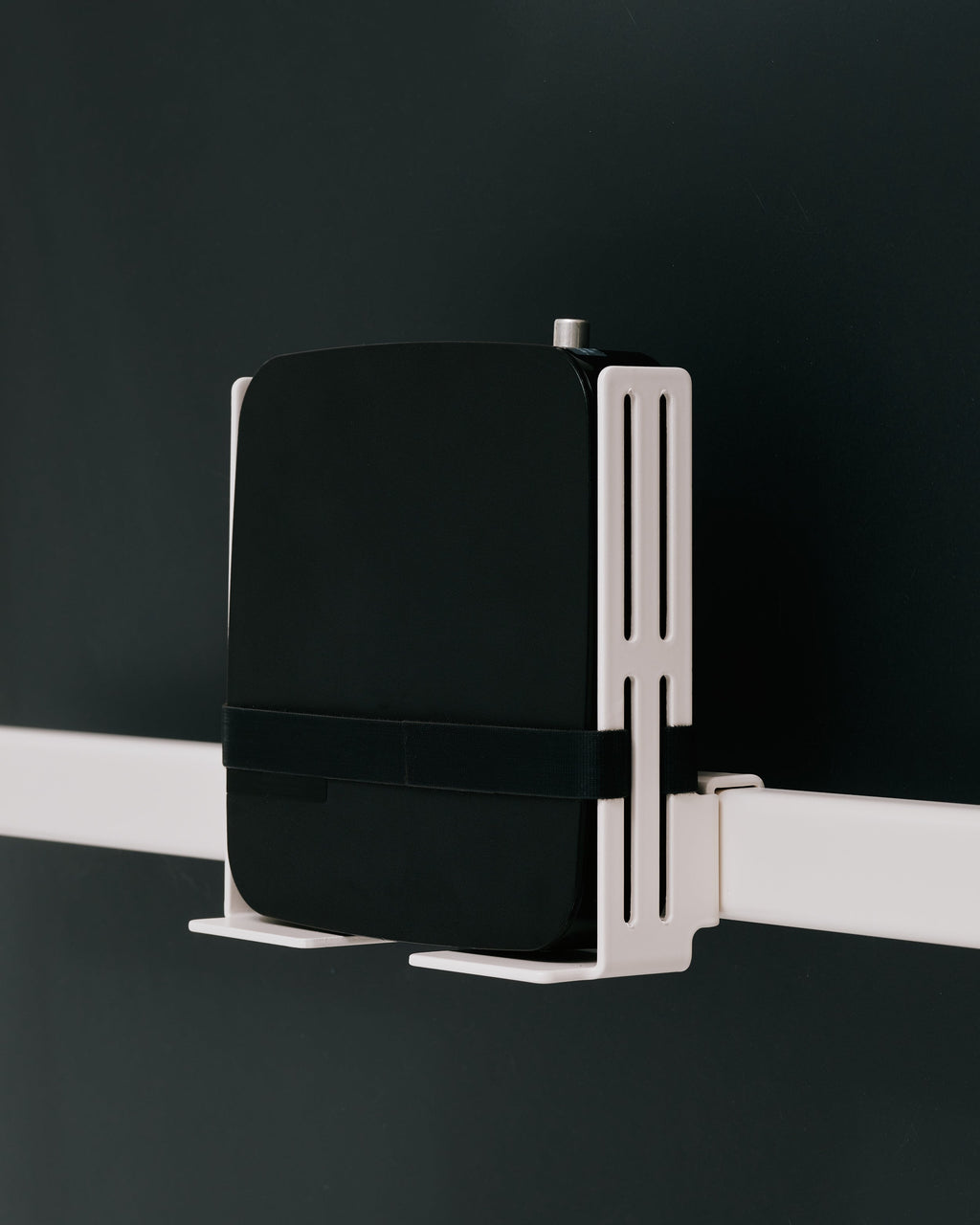 Oat Box Mount holding a black router with strap on a white rail, side angle against dark studio backdrop