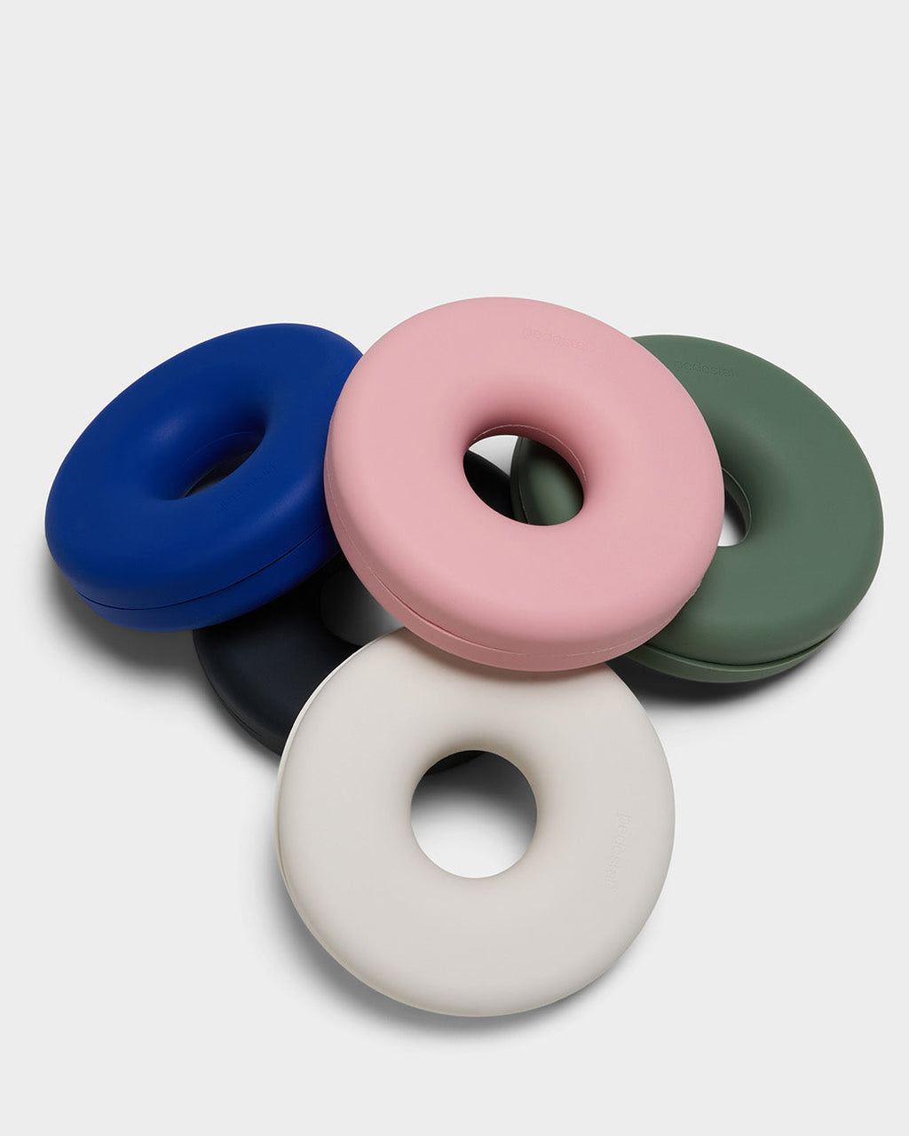 Pearl Cable Bagel cable manager stacked with pink, blue, green and black donut-shaped versions in a studio packshot
