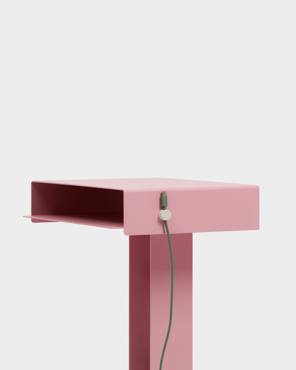 Pearl Cable Clip holding a green cable along the side of a pink metal side table in a studio setting