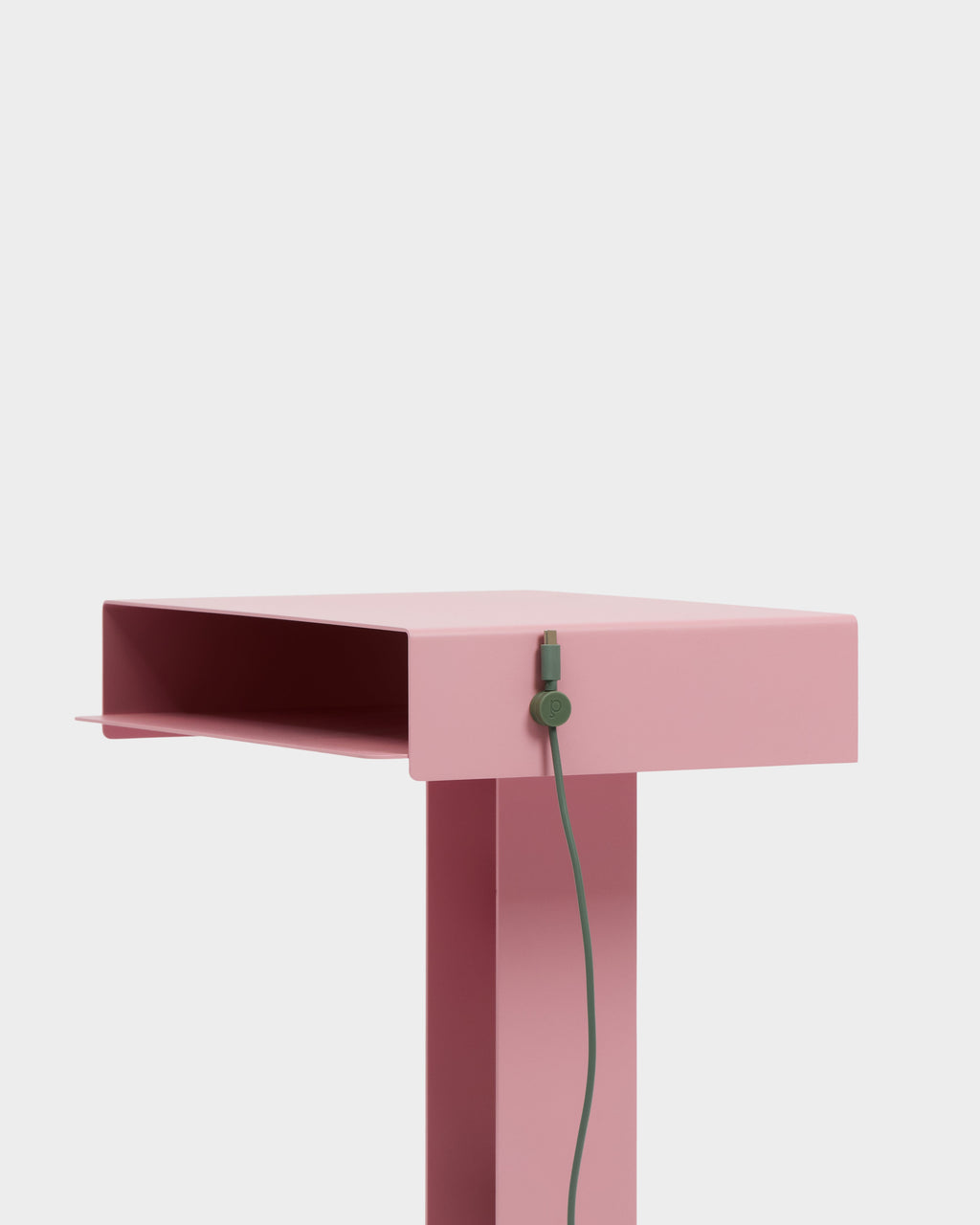 Mossy Green Cable Clip holding a green cable on the side of a pink desk, close-up studio detail shot