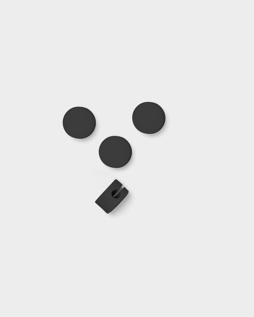 Three charcoal Cable Dots and one open cable clip, studio packshot from above on light grey