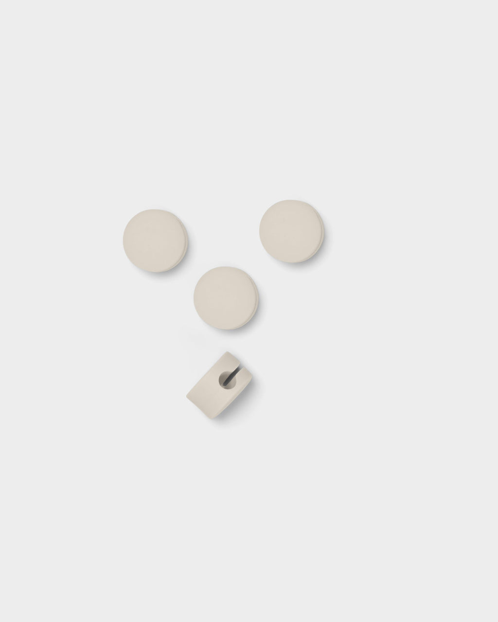 Three Cable Dots in Pearl shown flat with one flipped to reveal its cable slot, overhead studio packshot