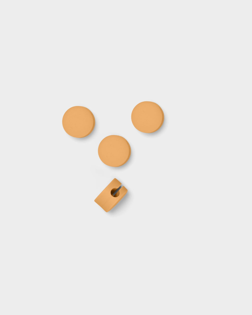 Three round Apricot Cable Dots and one slotted cable clip arranged on a light grey studio background, top-down view