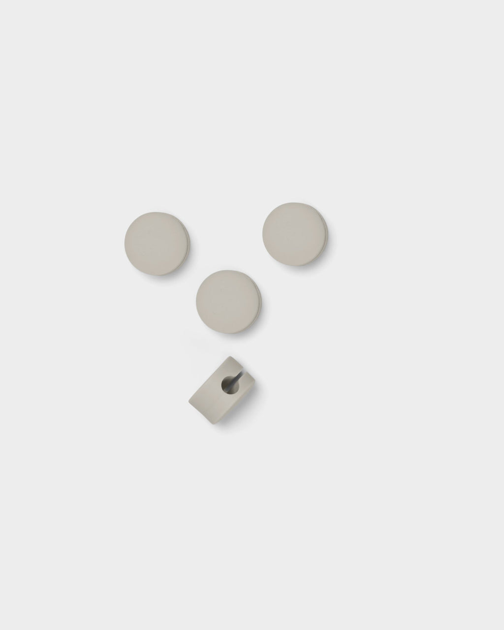 Four Cable Dots in Oat arranged on a white studio background, three round covers with one open cable clip