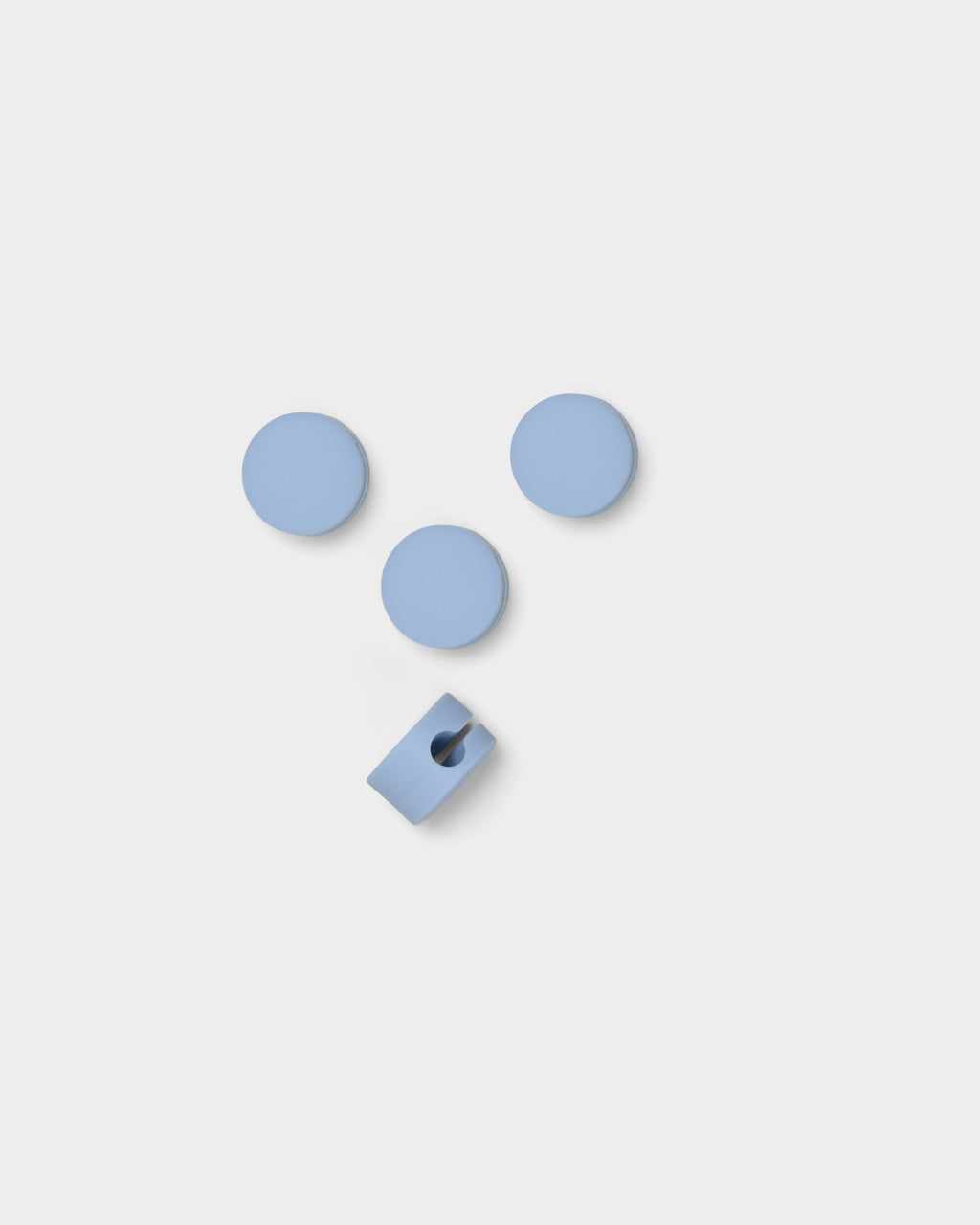 Four Cable Dots in Powder Blue arranged on a light studio backdrop, one turned to show its cable slot