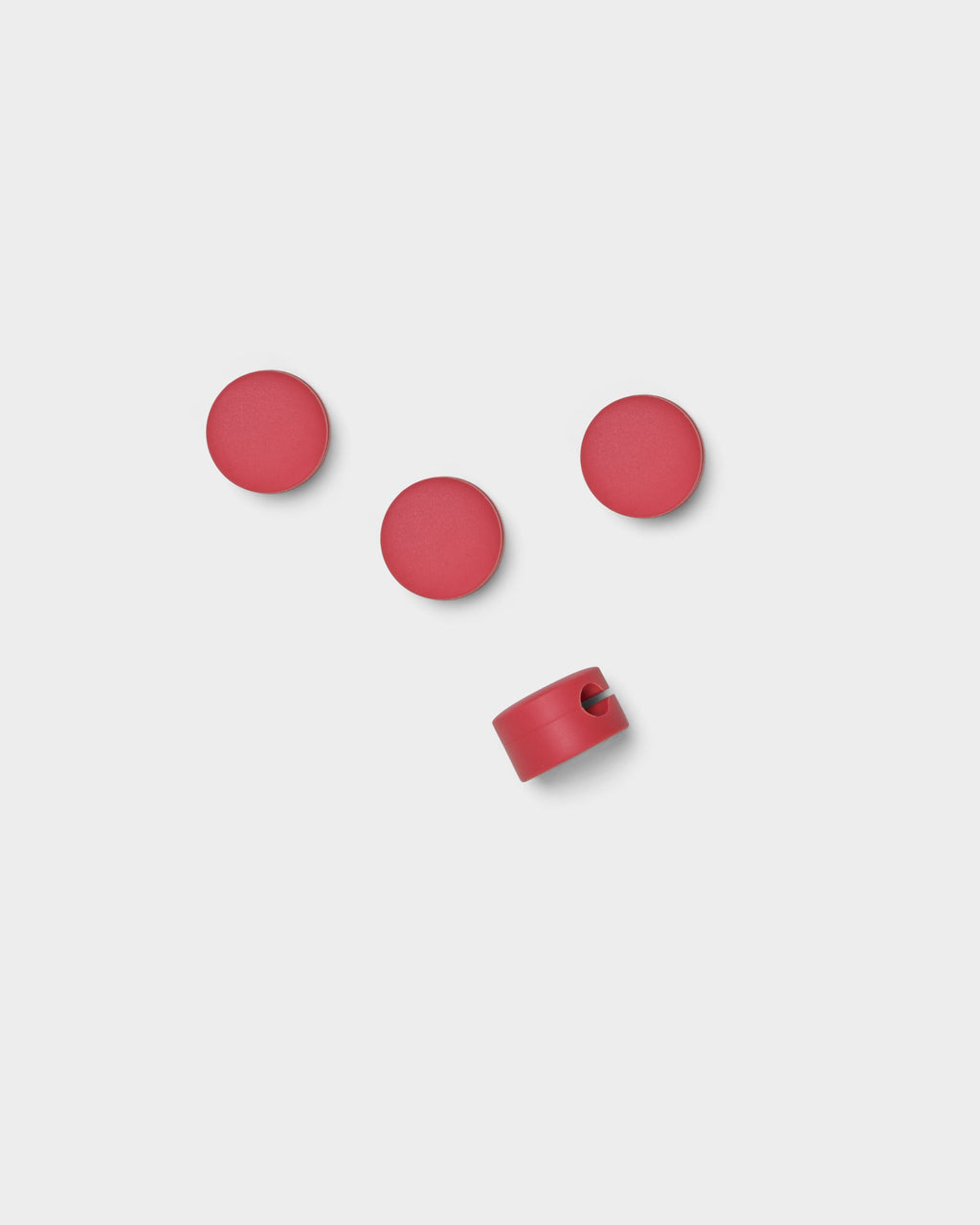 Four Cable Dots in Burnin' Red on a light studio background, three flat-side up and one tilted to show the cable slot