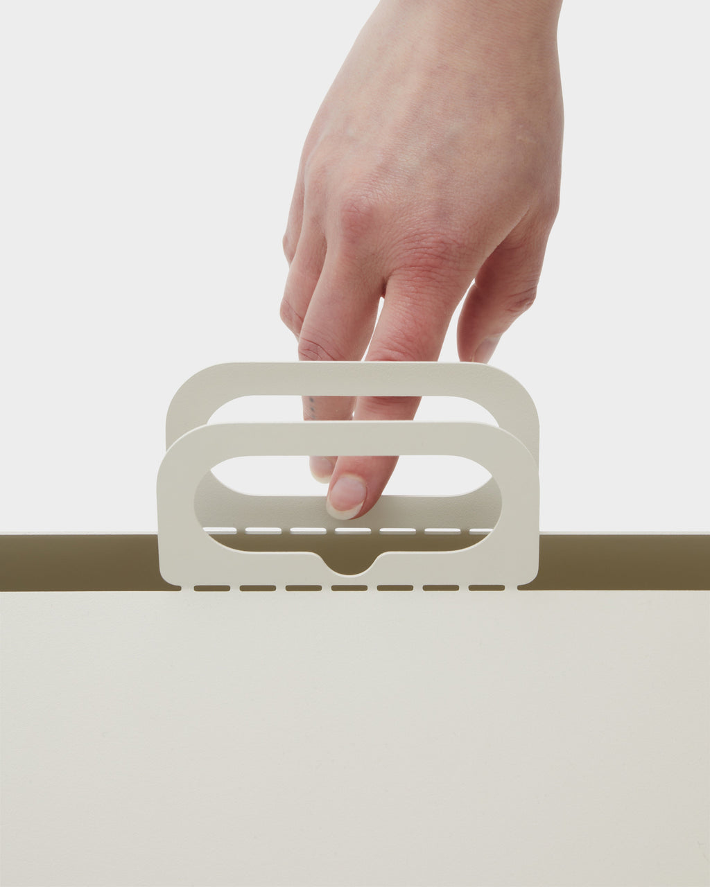 Hand lifting the Pearl Cable House by its dual folded handles in a bright studio close-up