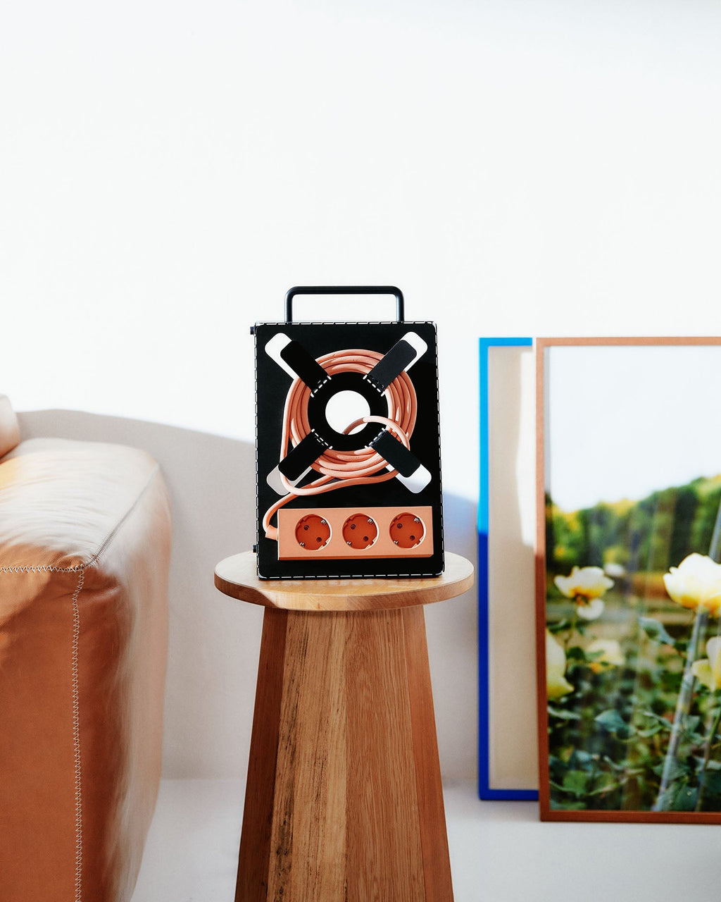Charcoal Cable Stand with coiled peach cord and triple socket, displayed on a round wood side table in a bright room