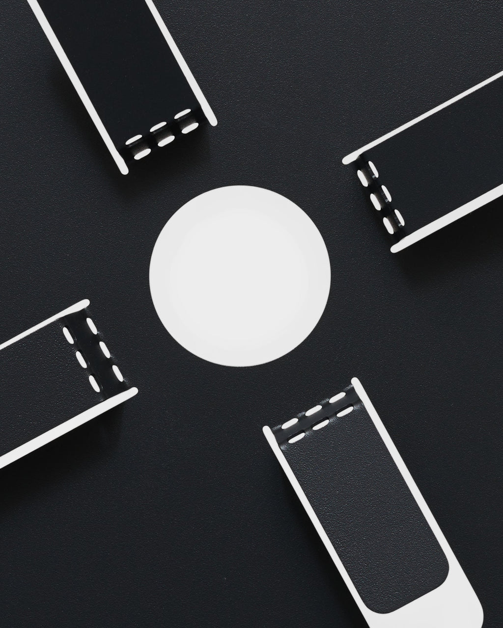 Charcoal Cable Stand shown flat-lay from above, four stitched black straps radiating around a white disc base