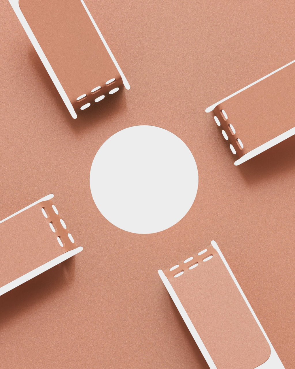 Four Dusty Rose Cable Stands arranged around a white circle on a matching rose studio backdrop, overhead flat lay
