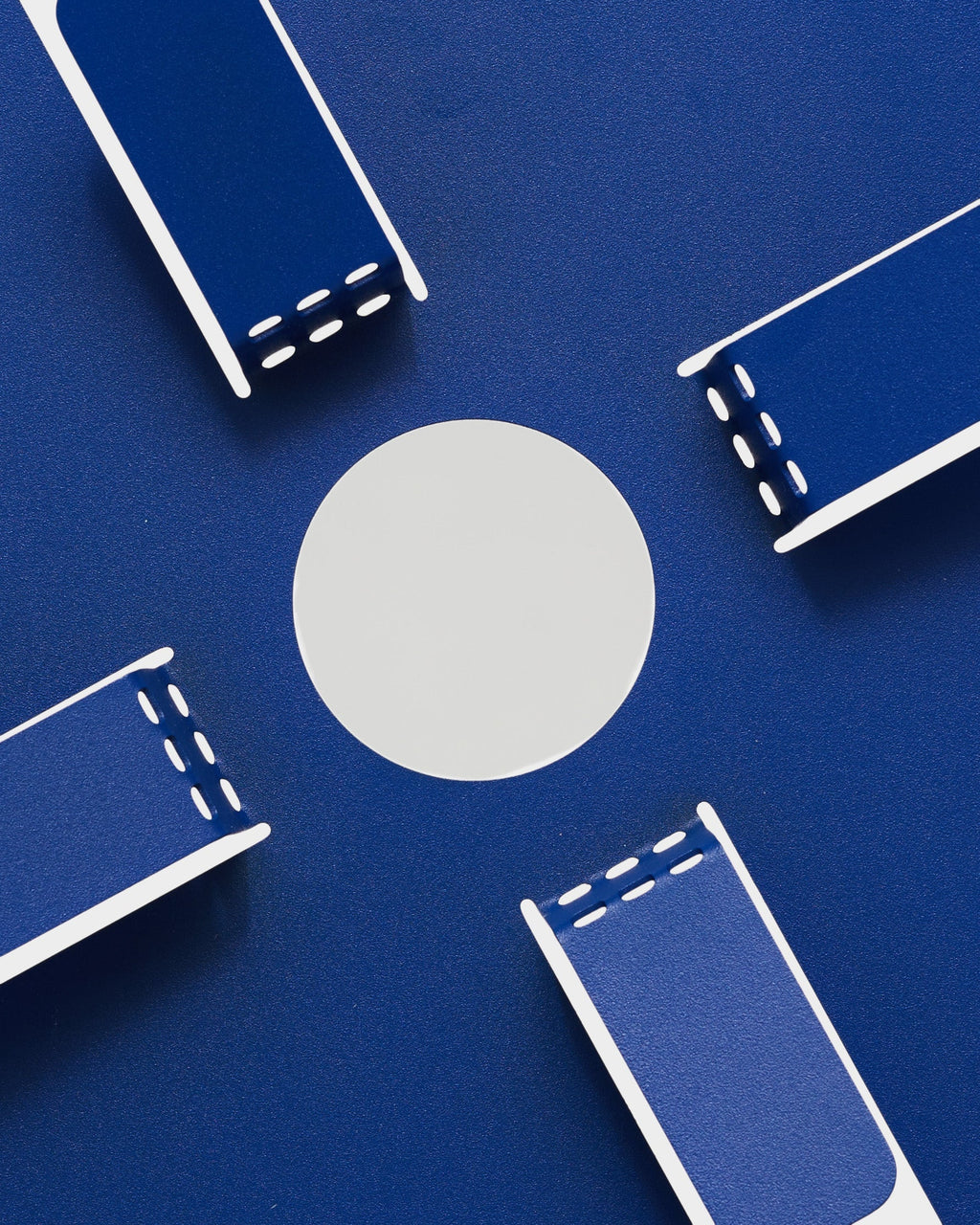 Four Ultra Marine Cable Stand pieces arranged around a white disc on a matching blue studio backdrop, overhead flat lay