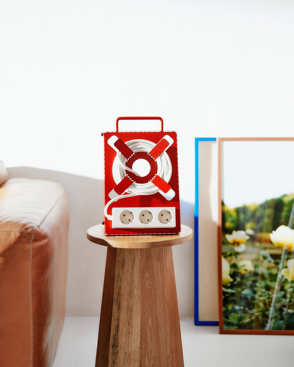 Fire Red Cable Stand with wrapped white cord and triple socket, styled on a wooden side table in a living room