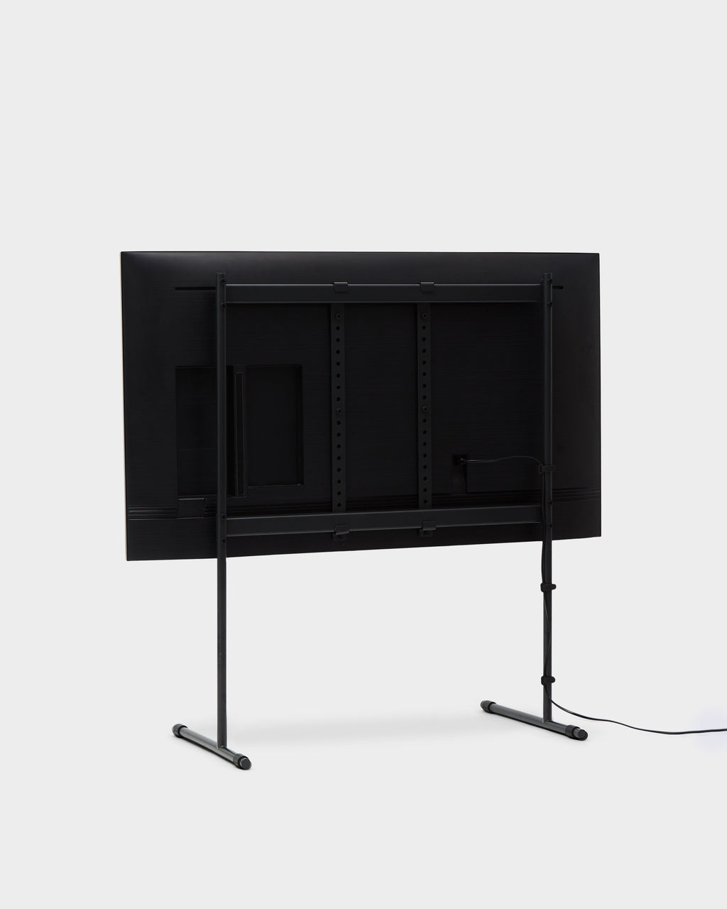 Charcoal Cable Ties securing a power cord along a floor stand's rear leg behind a mounted TV, studio packshot