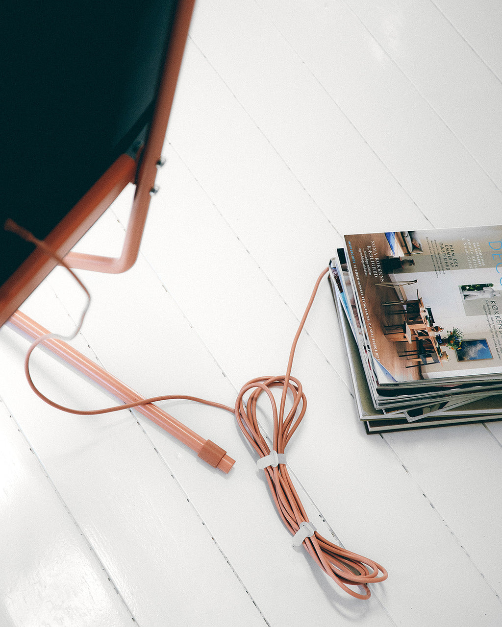 Charcoal Cable Ties bundling a terracotta cord on a white plank floor beside stacked magazines and a chair leg