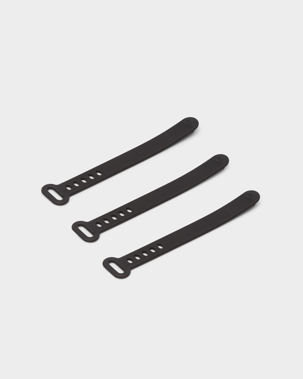 Three Cable Ties in Charcoal arranged diagonally on a light grey studio background, showing loop ends and adjustment holes