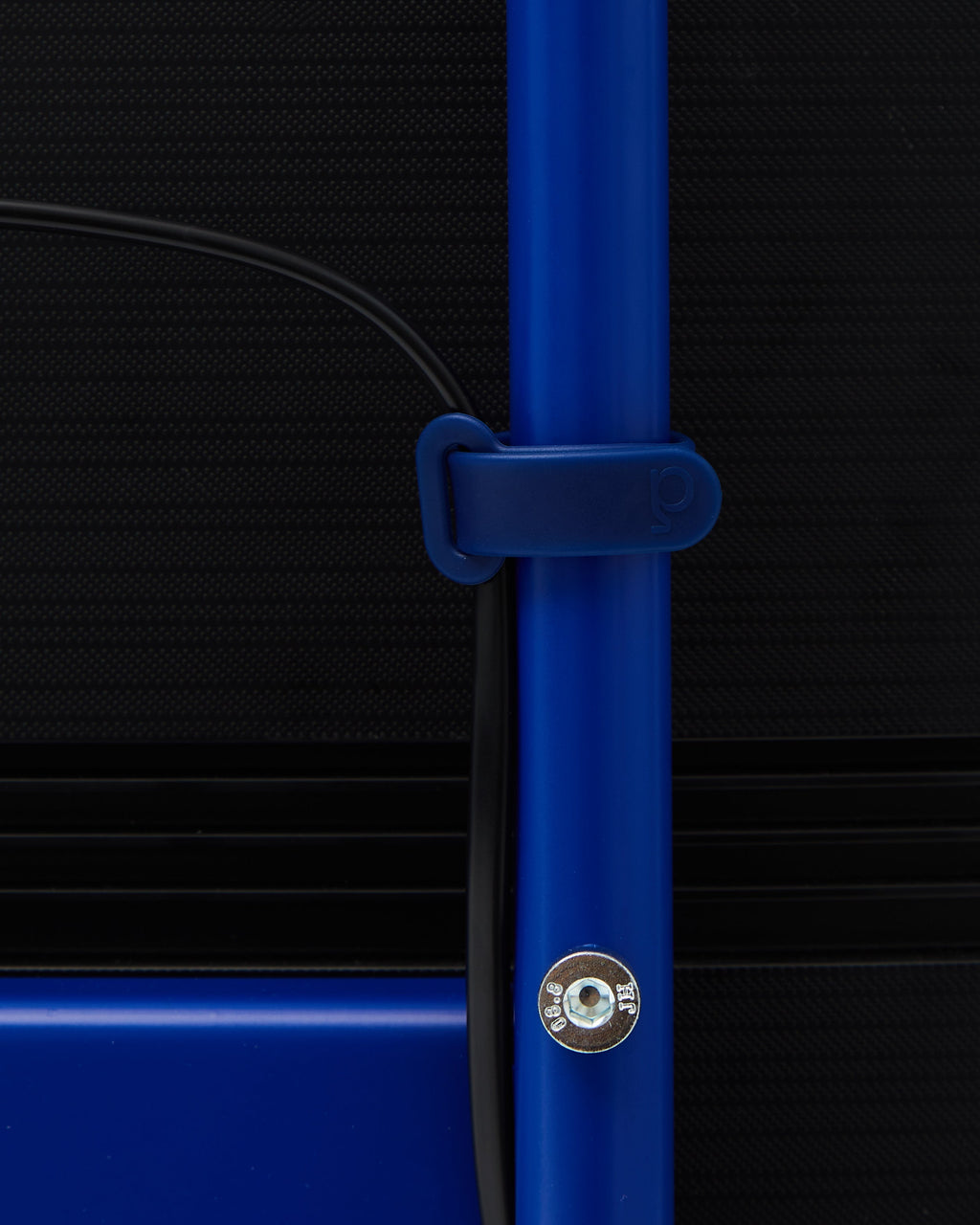 Ultra Marine Cable Tie close-up, wrapped around a blue desk leg holding a black cable against a dark panel