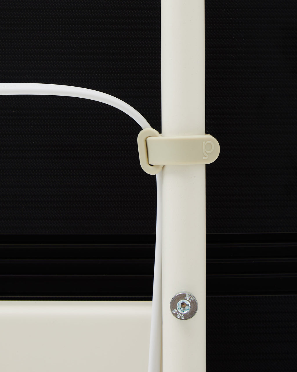 Pearl Cable Tie close-up, looping a white cable around a cream floor lamp stem against a dark backdrop