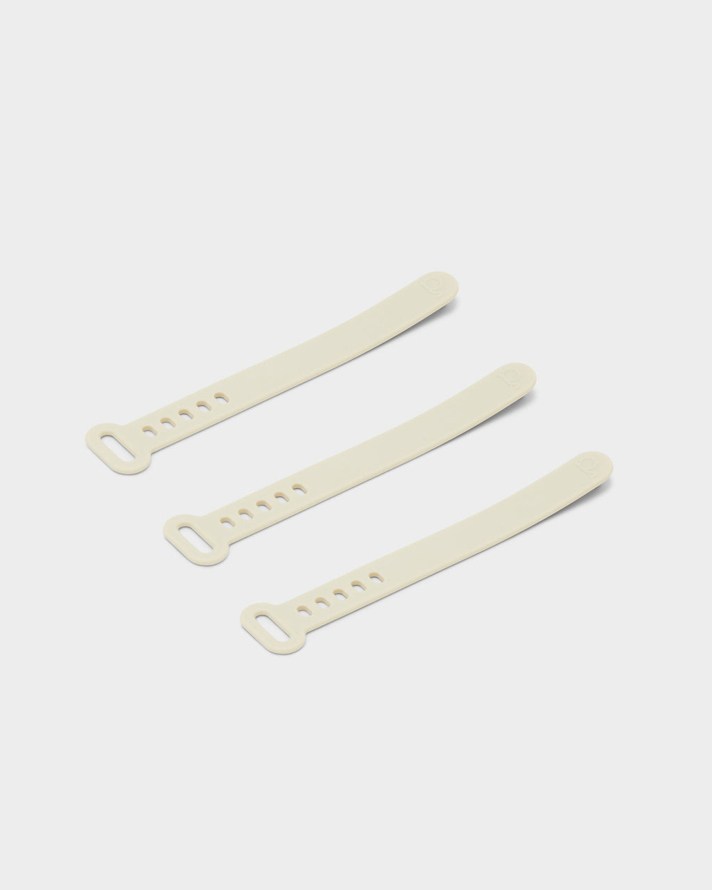 Three Pearl Cable Ties arranged diagonally on a light grey studio background, showing slotted ends and adjustment holes