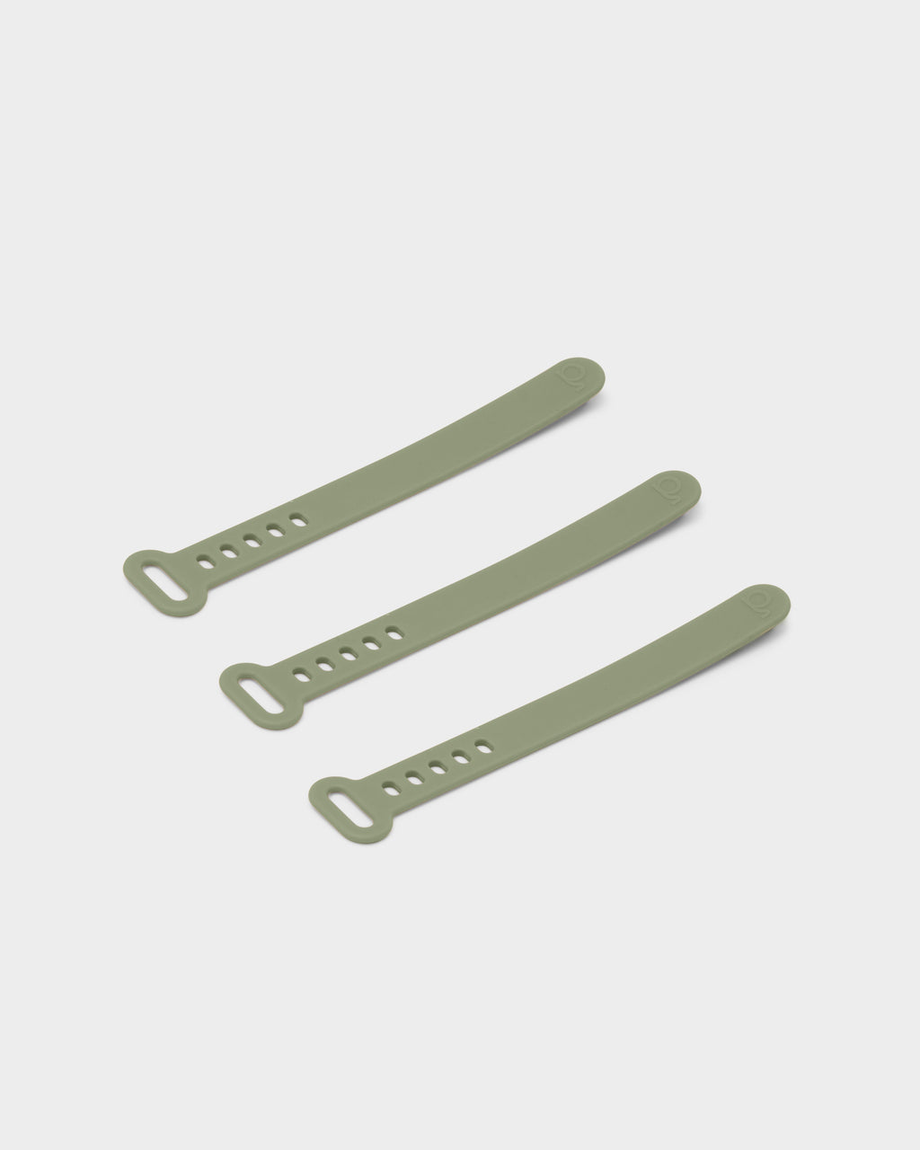 Three Mossy Green silicone cable ties arranged diagonally on a light studio backdrop, showing slotted loop ends