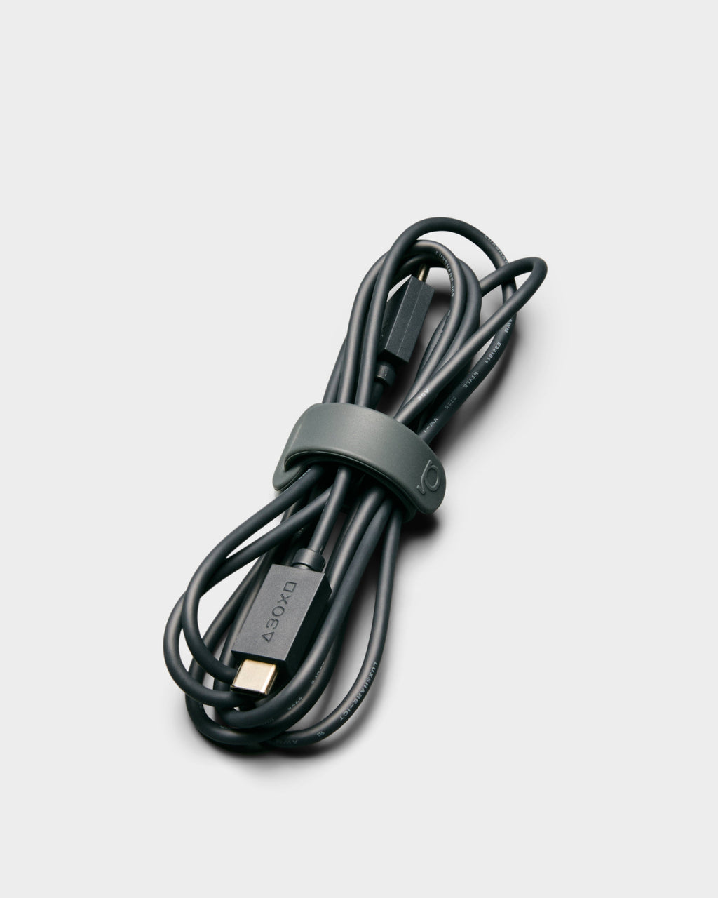 Legacy Gray Cable Tie holding a coiled black USB-C cable in a studio packshot, angled overhead view