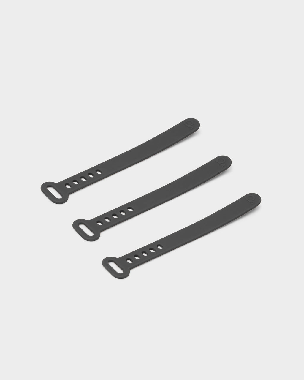 Three Legacy Gray silicone cable ties arranged diagonally on a light studio backdrop, showing slotted loop ends