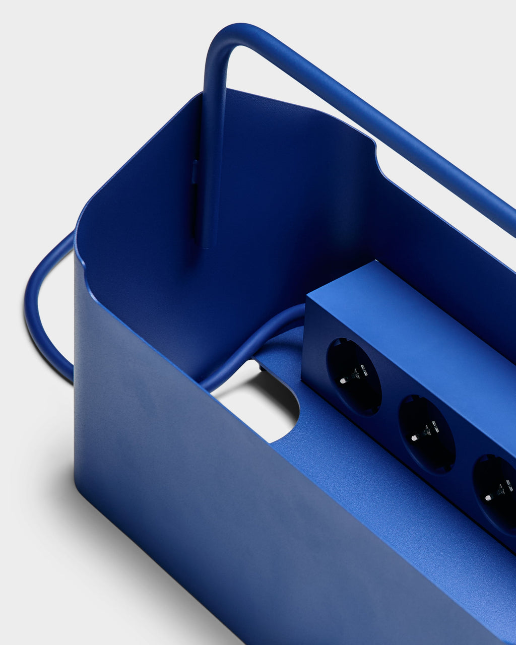 Close-up studio detail of the Ultra Marine Cable Villa, showing its curved handle, cable cutout and power strip inside