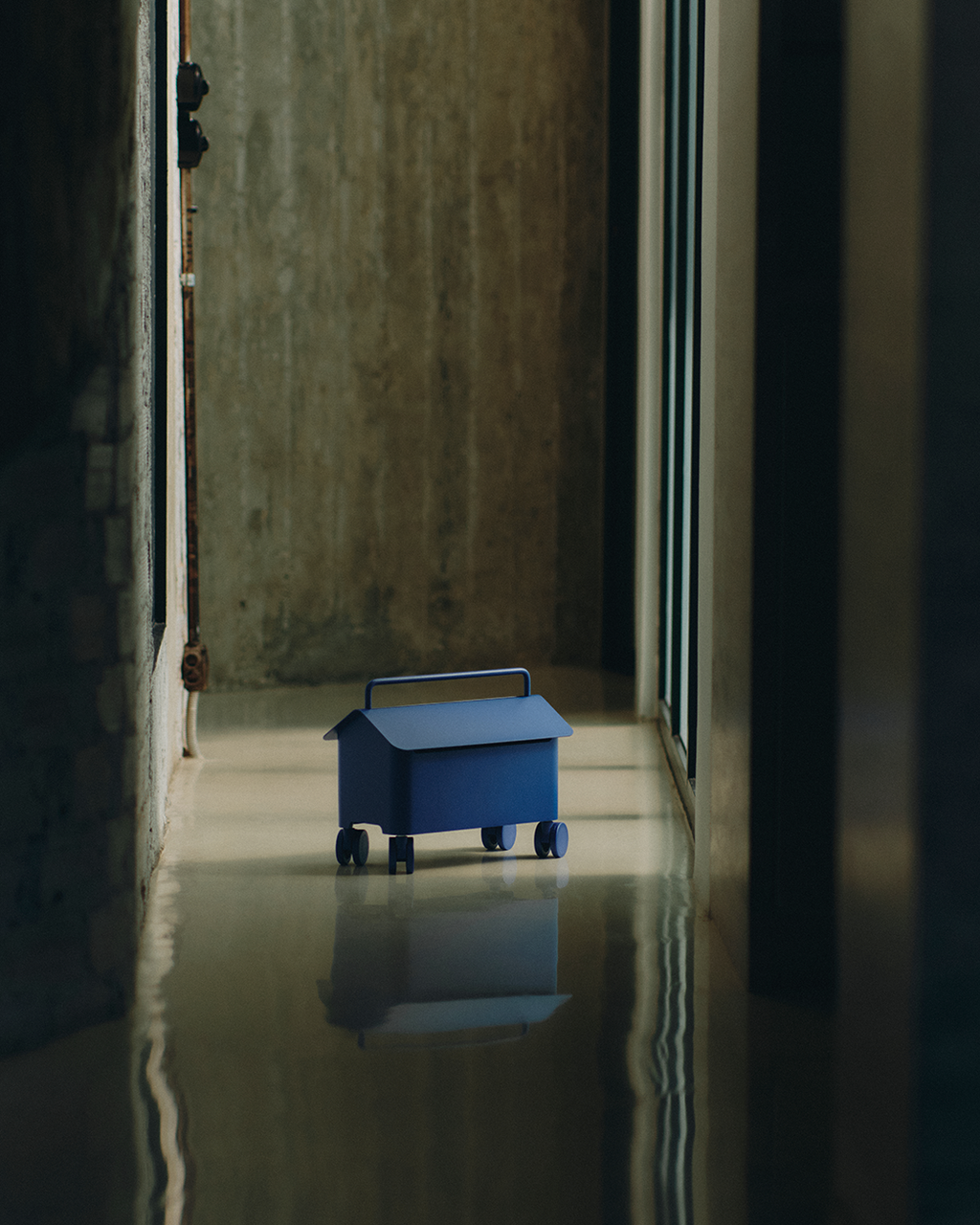 Cable Villa in Ultra Marine on castors, house-shaped cable box sitting on a polished concrete corridor floor