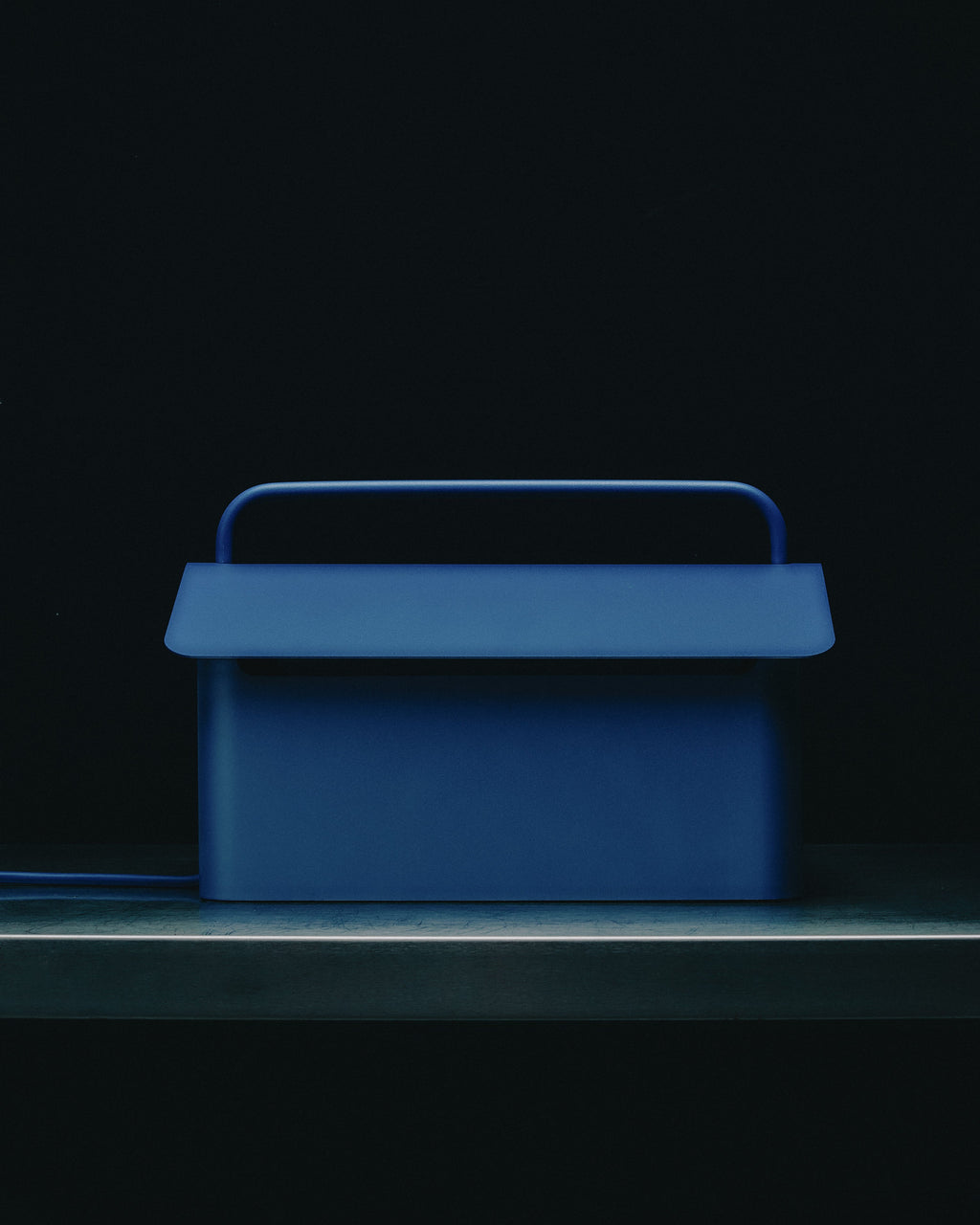 Ultra Marine Cable Villa cable box on a shelf in dim light, front view with carry handle and matching blue cord