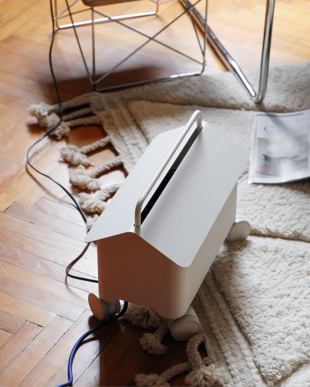 Pearl Cable Villa cable box on castors beside a wire chair and rug, lid open with cords routing out across parquet