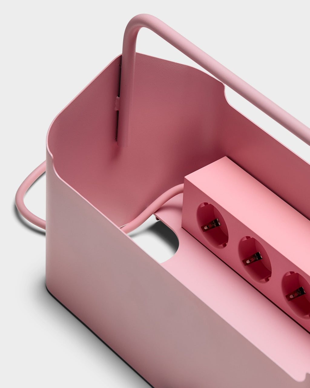 Close-up angled studio view of the Bubble Gum pink Cable Villa cable box, showing its carry handle and power strip sockets