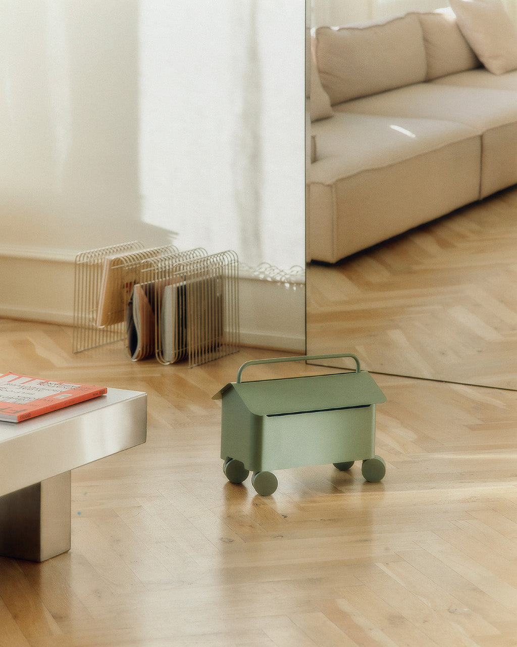 Cable Villa in Mossy Green on wheels in a sunlit living room, herringbone floor, mirror and sofa behind