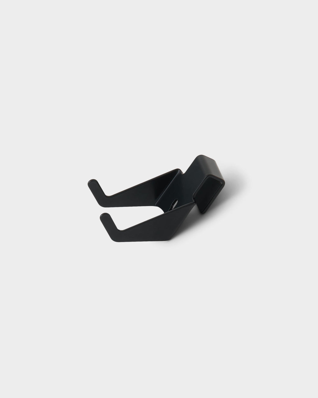 Charcoal Controller Mount shown at an angle on a light studio backdrop, highlighting its dual-prong hooks and folded clip