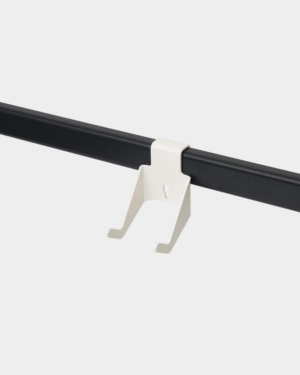 Pearl white Controller Mount clipped onto a black wall rail, studio packshot angled view showing twin hook prongs