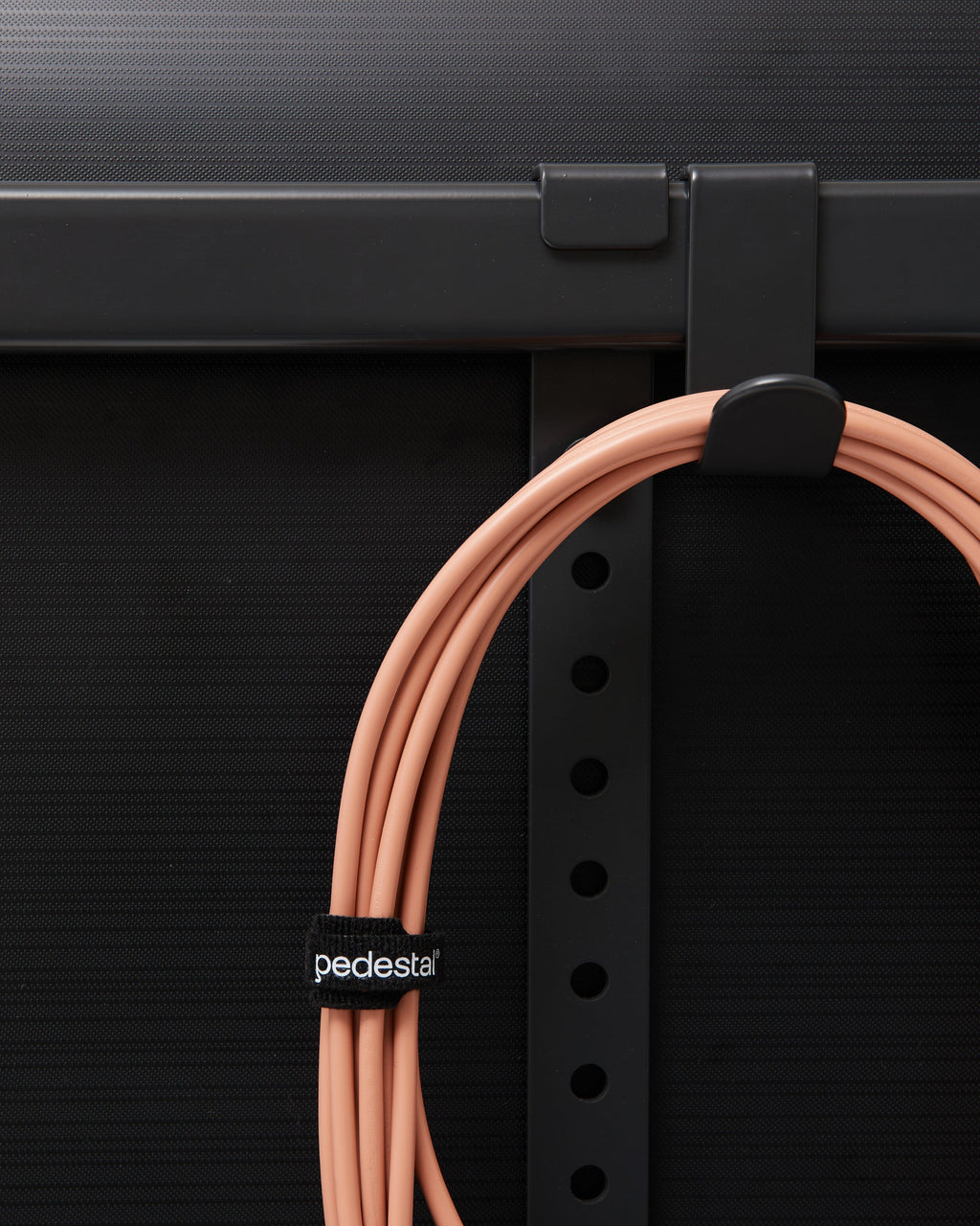 Charcoal Hook Mount clipped to a black rack rail, holding a coiled salmon cable secured with a pedestal strap