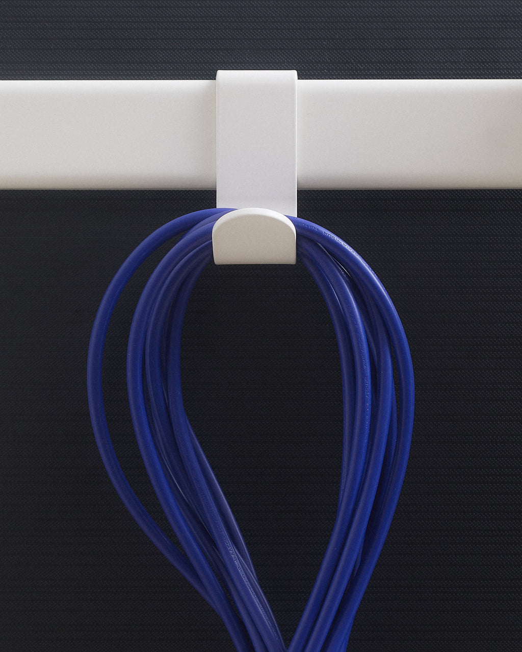 Pearl Hook Mount clipped over a white rail, holding coiled blue cable against a dark studio backdrop