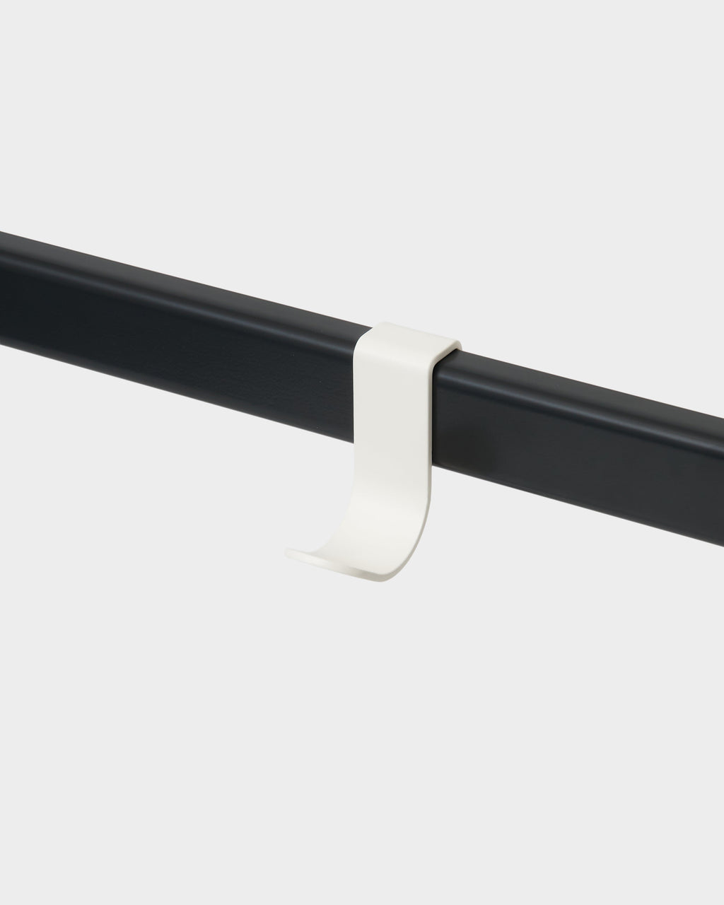 Pearl Hook Mount clipped onto a black rail in a studio packshot, angled view showing its curved J-shaped hook
