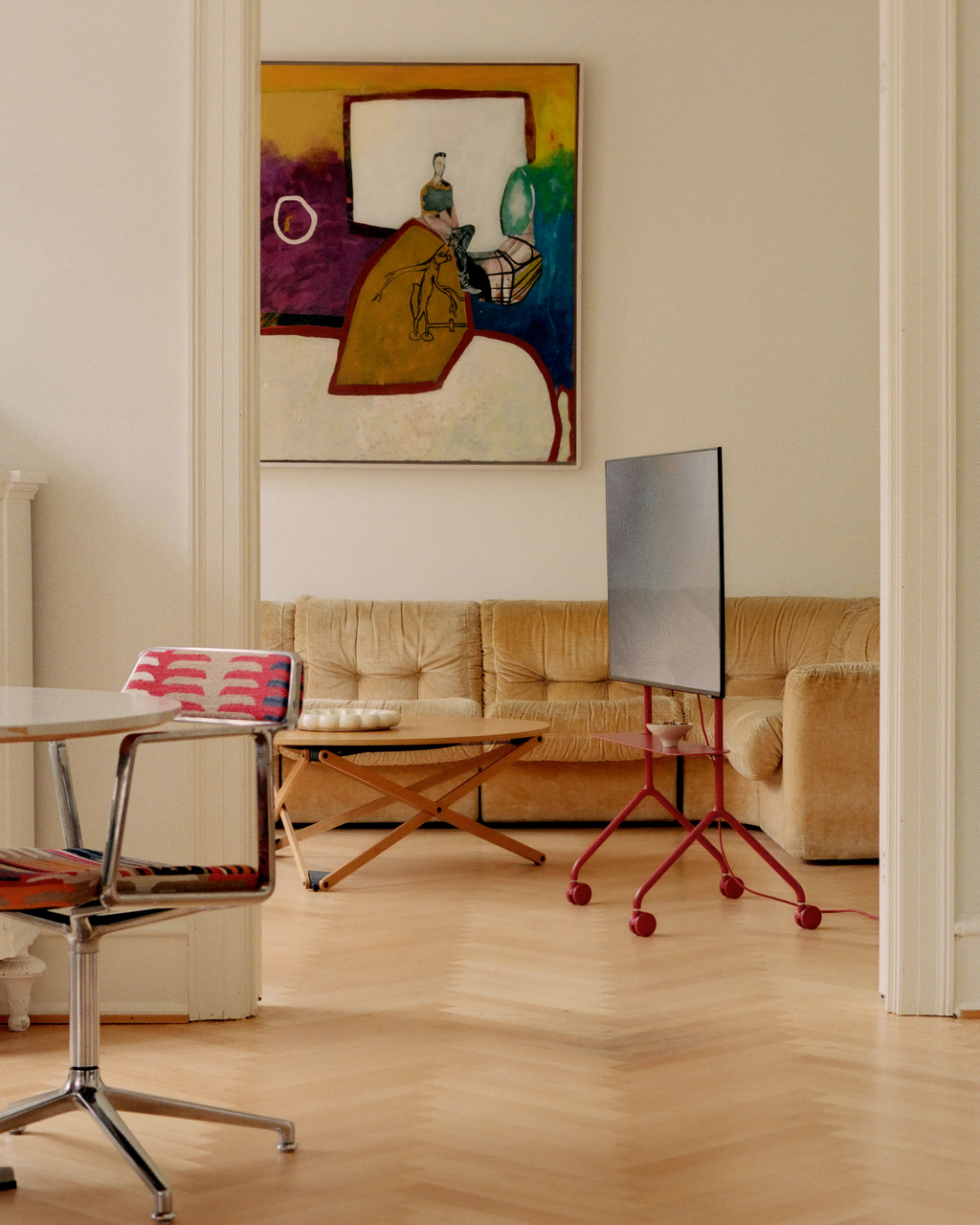 Moon Light TV stand in Burnin' Red on castors holding a flatscreen in a bright living room with velvet sofa and art