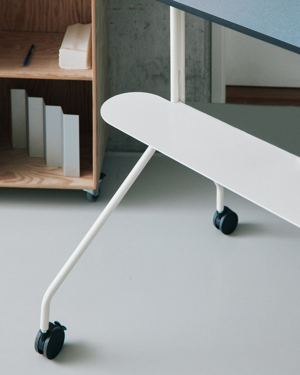 Close-up of Moon PRO in Pearl showing white base, angled legs and black locking casters in a bright studio space