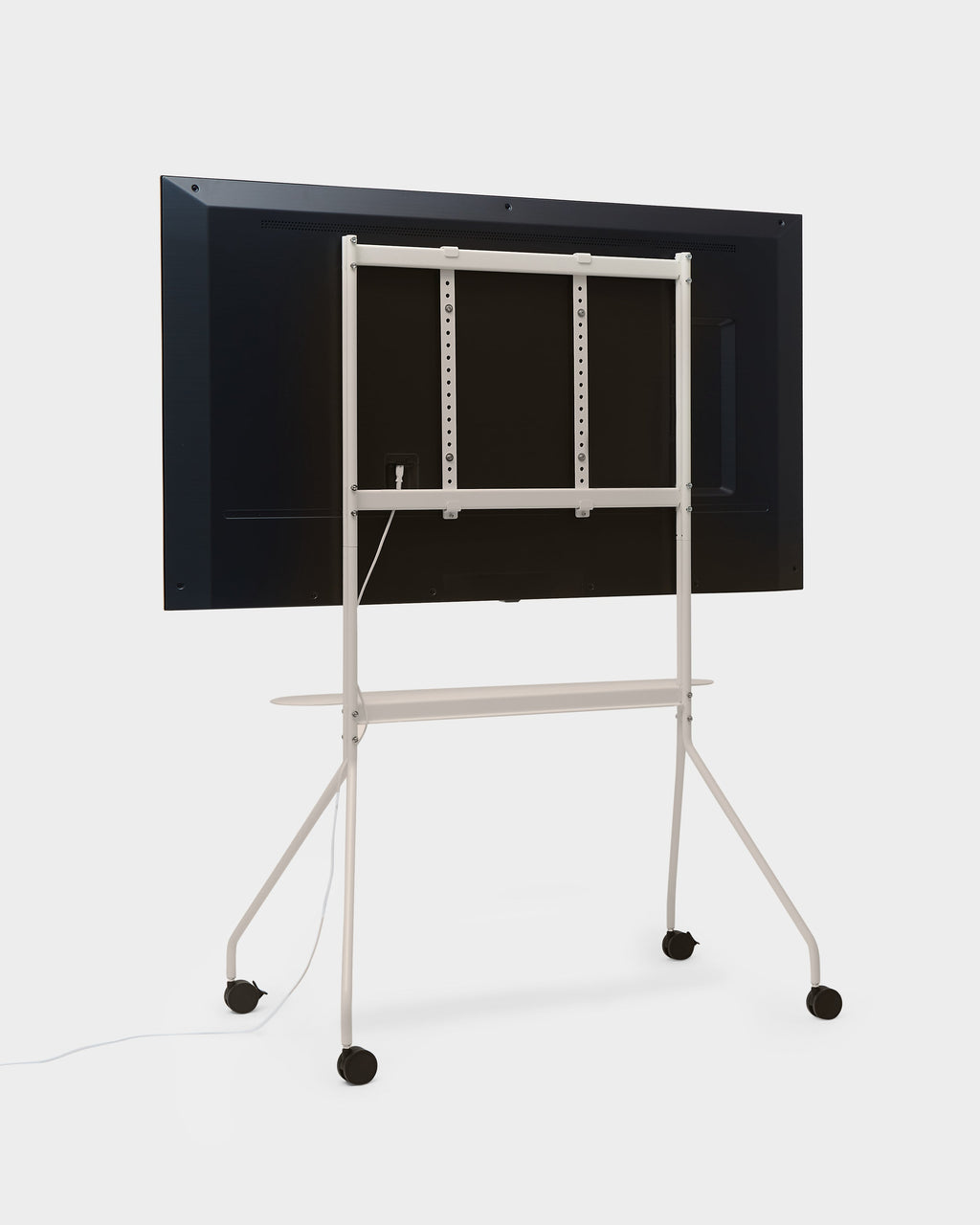 Rear view of Moon PRO TV stand in Oat with mounted display, tripod legs, casters and shelf in a studio packshot